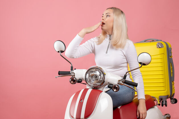 身体前视图：坐在轻便摩托车上的年轻女士 好奇的粉色墙壁奇迹轻便摩托车年轻女士