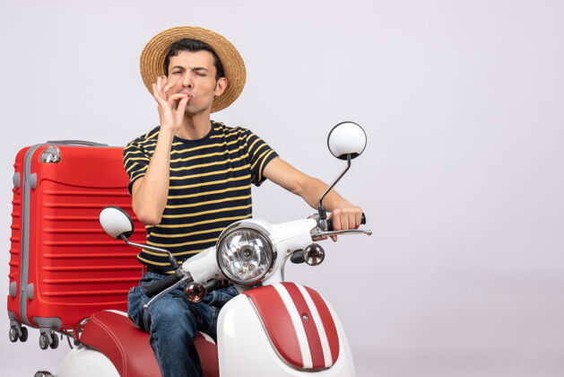 前面骑着轻便摩托车戴着草帽的年轻人的正面图 做着美味的招牌轻便摩托车稻草车辆