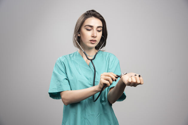 医生女医生用听诊器检查自己的灰色背景高质量的照片检查制服女性