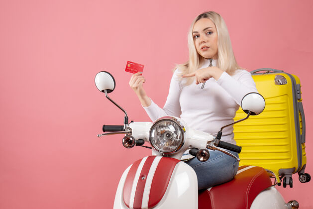 坐着前视图：骑着轻便摩托车的金发女孩指着卡片轻便摩托车摩托车成人