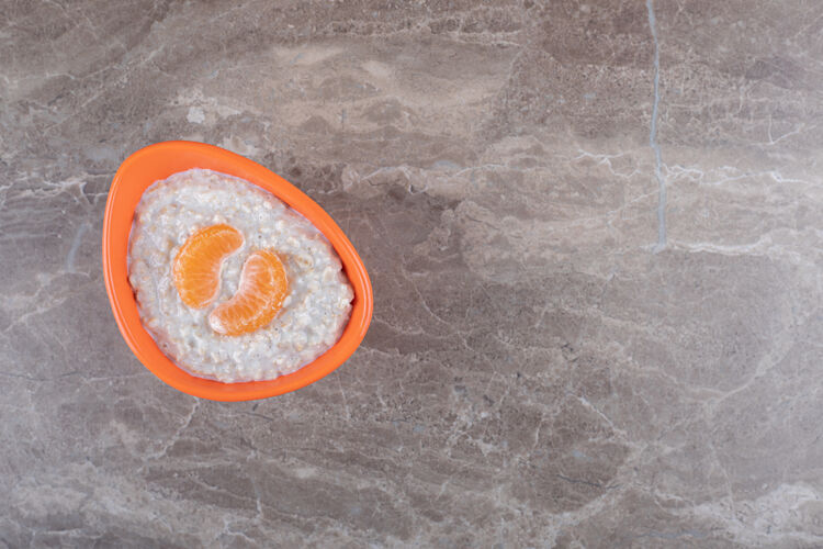 橙子把橙子片放在碗里的粥上 放在大理石背景上美味营养风味