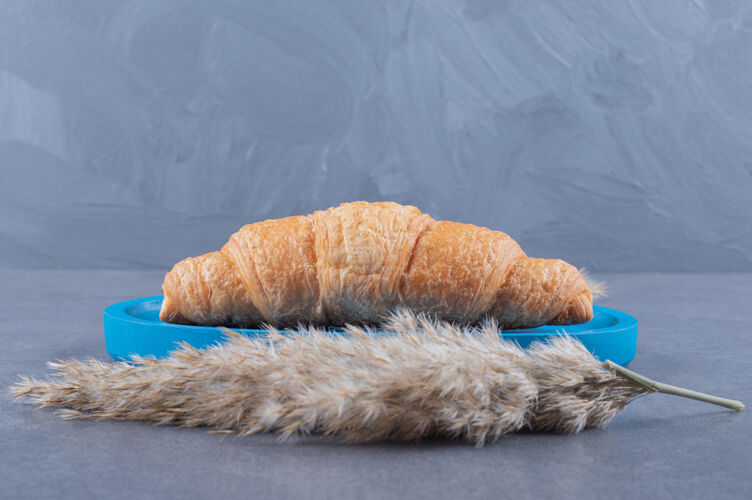 桌子新鲜出炉的法式羊角面包放在蓝色木板上美食美味许多