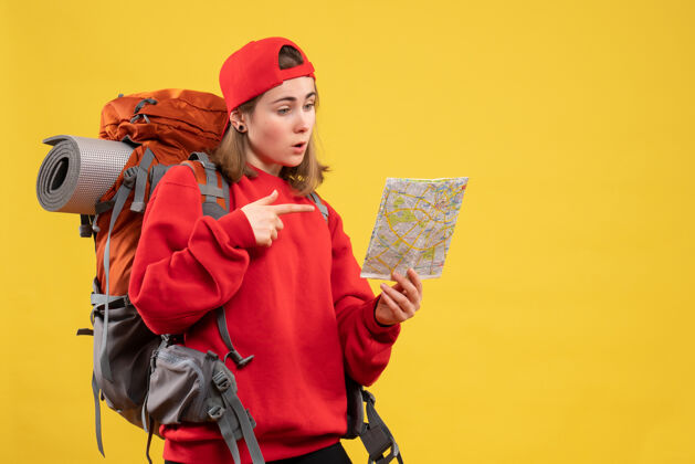 地图正面图漂亮的女旅行者背着背包指着地图帽子成人前面