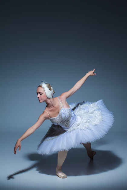 戏剧芭蕾舞演员在蓝色背景下扮演白天鹅的肖像优雅天鹅芭蕾舞演员