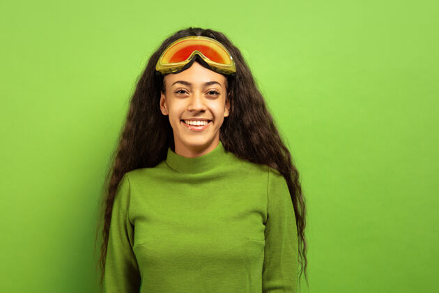 女孩以绿色工作室为背景 黑色皮肤的非洲裔年轻女子的滑雪面具肖像人类情感的概念 面部表情 销售 广告 冬季运动和假期微笑 看起来很快乐女性乐趣美国