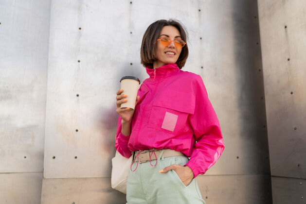 人时尚运动的短发女人拿着咖啡杯摆姿势肖像时髦城市