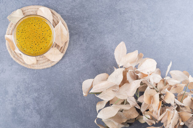 玻璃杯新鲜橙汁的顶视图 灰色背景上有装饰性的叶子果汁健康水果