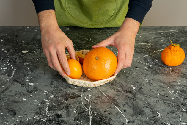烹饪男性手拿多汁的橘子水果放在大理石桌上各种厨师刀