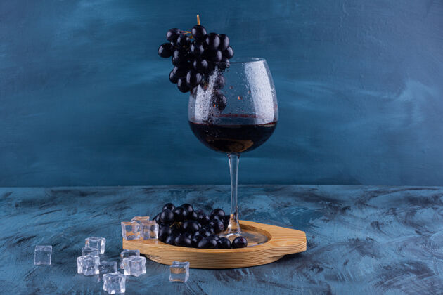 红酒大理石桌上摆着一杯红葡萄酒和黑葡萄葡萄藤浆果健康