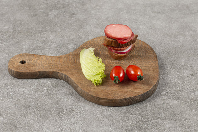 蔬菜在木板上用黑麦面包和西红柿切意大利腊肠黄油美味小吃