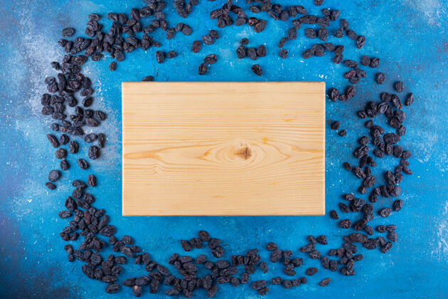 健康蓝色桌子上放着一堆黑葡萄干和木板框架柔软烹饪