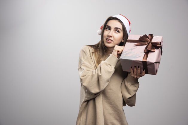 表情一个年轻的女人为一份圣诞礼物而兴奋年轻携带人