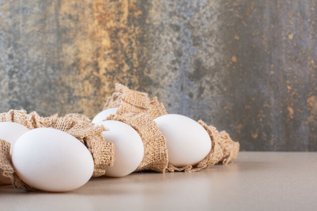 未经料理的新鲜的生鸡蛋放在米色的桌子上食物蛋壳白