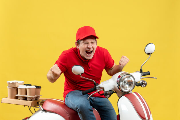 背景前视图紧张的年轻人穿着红色衬衫和帽子 在黄色背景下传递命令人人摩托车