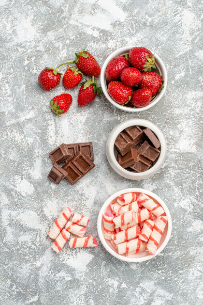 糖果顶视图碗草莓巧克力糖果和一些草莓巧克力糖果在灰白色的地面上新鲜多汁浆果
