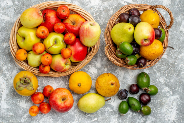 桃顶视图红色和黄色的苹果 李子 梨和柿子在柳条筐里 也在地上磨碎食用水果农产品