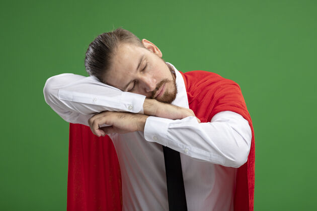 手势年轻的超级英雄戴着领带 闭着眼睛 头戴在胳膊上 在绿色的草坪上表现出睡觉的姿势关闭领带睡眠