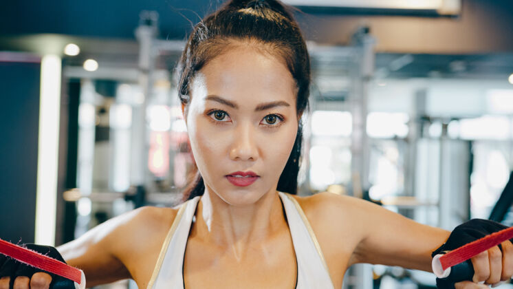 拉年轻的亚洲女士在健身班做健身机电缆交叉电缆举举锻炼
