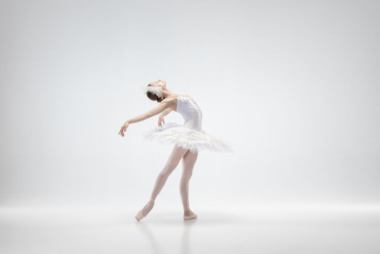 灵活优雅的经典芭蕾舞演员在白色的工作室背景下跳舞穿着柔软衣服的女人像一只白天鹅优雅 艺术家 运动 动作和运动的概念看起来没有重量优雅愉悦情侣
