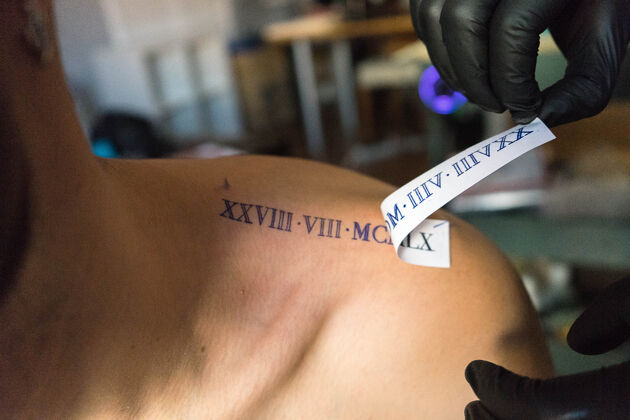 肩膀特写镜头的纹身艺术家放置在客户的肩膀上的设计艺术家皮肤纹身