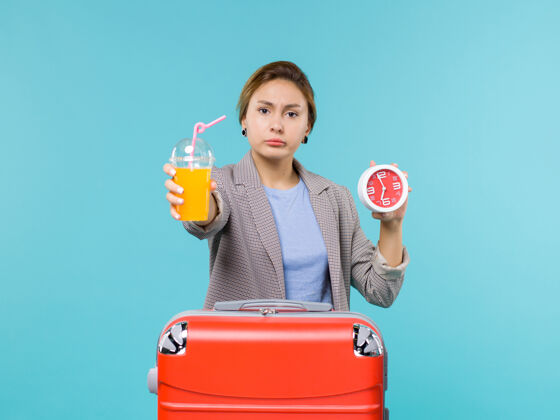 航行正面图：度假中的女性手持新鲜果汁和时钟在蓝色背景下远航远航度假假期旅行旅行
