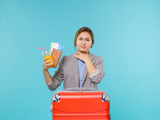 微笑正面图：度假中的女性手持新鲜饮料和蓝色背景海上度假旅行的机票前面航行旅游