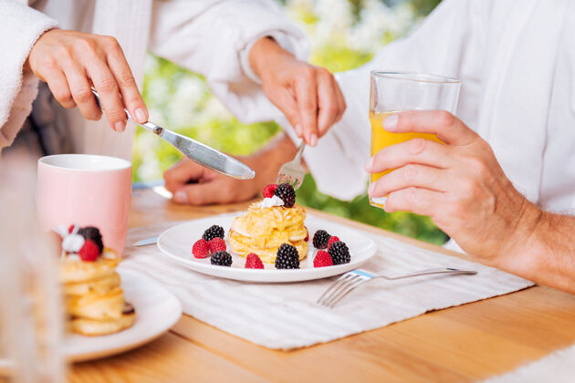 周末早餐有薄煎饼成熟的男人早餐有蜂蜜和浆果的热煎饼和一杯橙汁浆果情侣刀