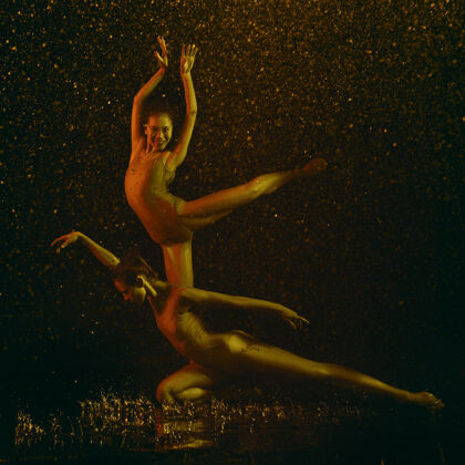 下降微笑两个年轻的女芭蕾舞演员在水滴和浪花下白种人和亚洲模特在霓虹灯下一起跳舞芭蕾舞和当代舞蹈概念创意艺术照片编舞拥抱表演