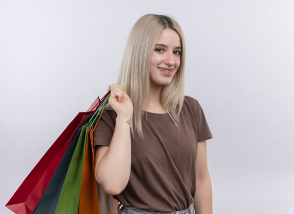 年轻微笑的金发女孩戴着牙套 肩上扛着购物袋 在一片空白的空间里复制微笑购物包