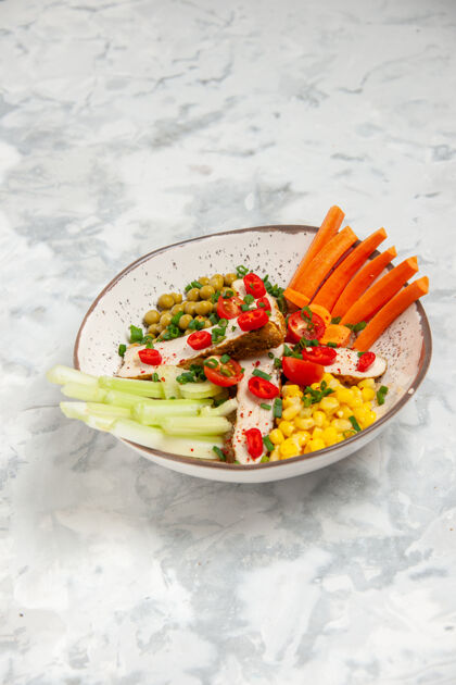 膳食白色表面的盘子上有各种配料的美味沙拉的垂直视图健康沙拉晚餐