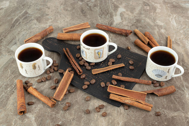 烤浓缩咖啡 肉桂棒和咖啡豆在大理石表面热浓缩咖啡马克杯