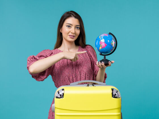 举行前视女性在旅行中拿着地球仪在蓝色背景上旅行旅行旅行旅行旅行旅行旅行女人海前面蓝色航行