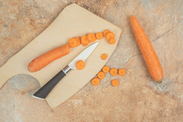 刀一块插着胡萝卜片和刀的木制砧板饮食食物胡萝卜