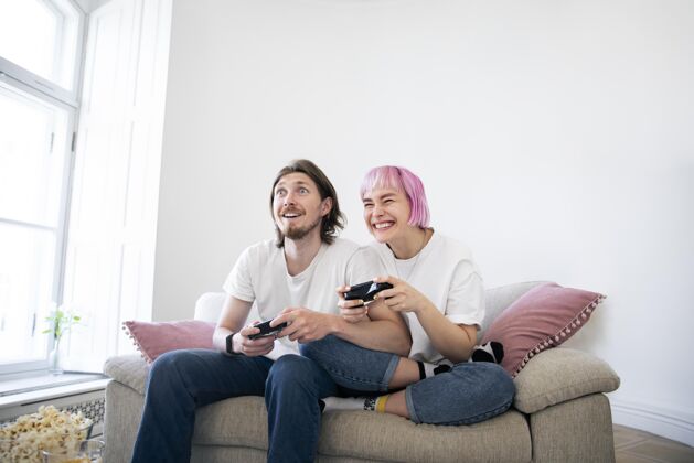 乐趣可爱的情侣在沙发上玩电子游戏在线科技女人