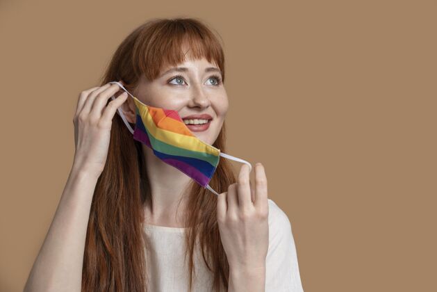 平等戴着彩虹医学面具的年轻红发女人同性恋自豪宽容世界自豪
