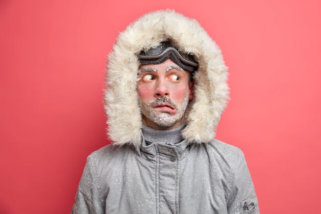 夹克情绪困惑的男人把头捂着嘴唇 一边看着因低温发抖需要保暖的灰色夹克和皮帽霜保温瓶风