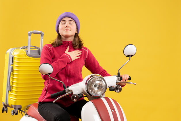 成人前视图幸运的年轻女子骑着轻便摩托车把手放在胸前人胸车