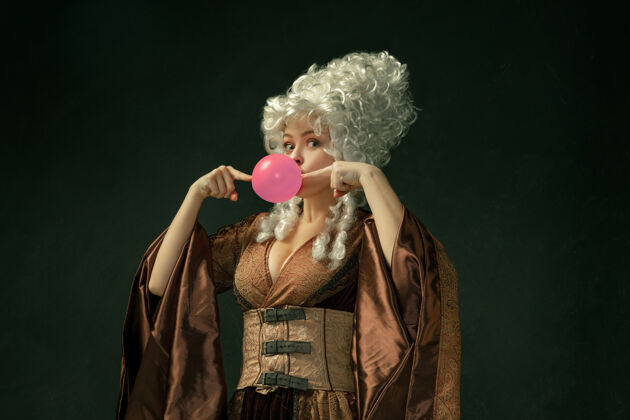 历史粉红色的泡泡糖深色背景上穿着棕色复古服装的中世纪年轻女子肖像女模特 公爵夫人 皇室成员时代 现代 时尚 美丽的对比概念皇室优雅命运