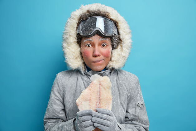 寒冷图为冻红脸蛋的年轻女子穿着温暖的夹克 为寒冷的冬天准备鱼片 需要温暖女人漂亮美丽