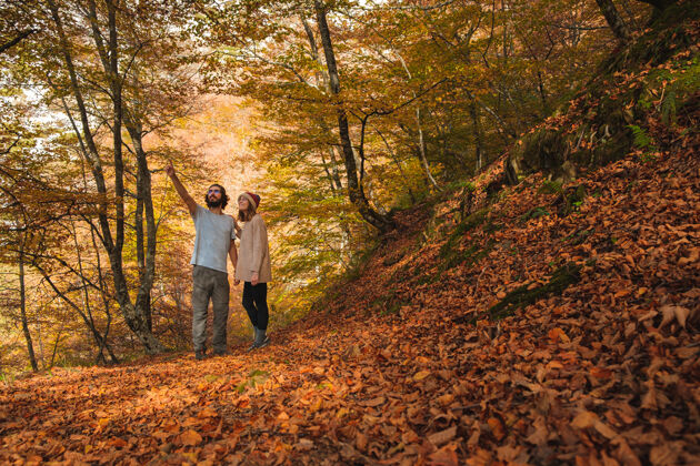 男性一对年轻夫妇欣赏秋天树叶覆盖的森林的景色季节秋天秋天