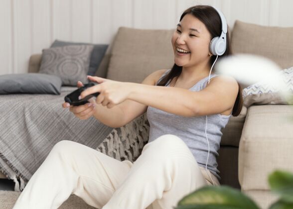 水平女人和控制器玩电子游戏室内玩耳机