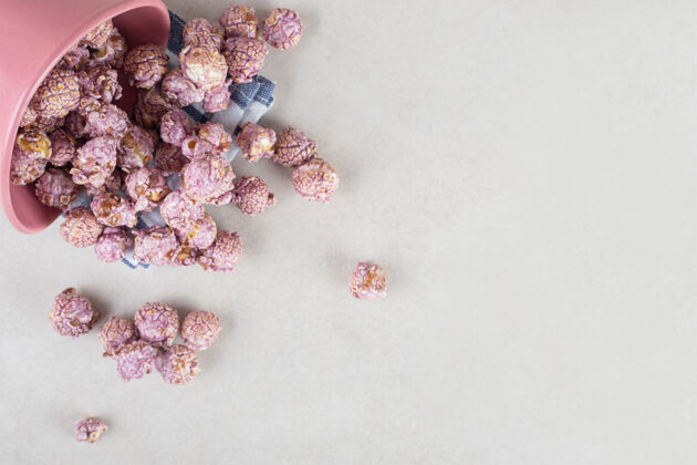 顶视图满满一碗紫色爆米花倒在折叠的毛巾上 放在大理石桌上零食不健康爆米花