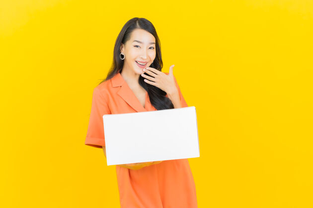 泰国肖像美丽的年轻亚洲妇女与箱准备装运黄色控股笔记本电脑盒子