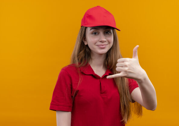 红色穿着红色制服的自信的年轻送货女孩在孤立的橙色空间和复印空间上做呼叫手势女孩复制自信