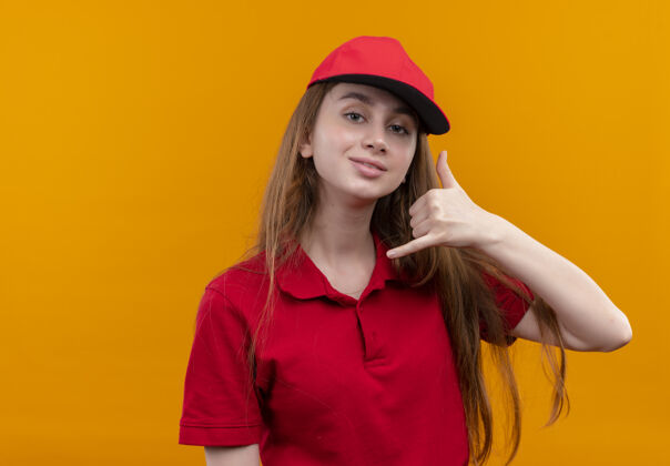 橙色穿着红色制服的自信的年轻送货女孩在孤立的橙色空间和复印空间上做呼叫手势自信女孩制服