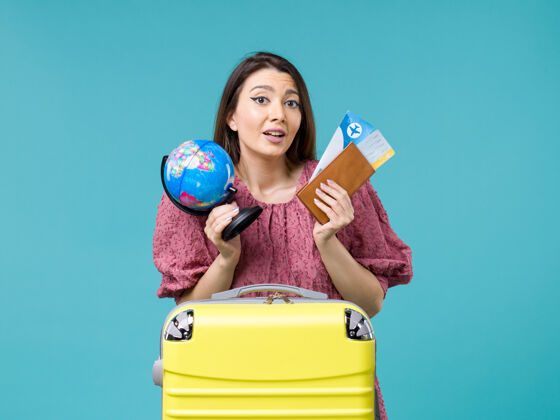 球前景度假女拿着地球仪和飞机票在蓝色书桌上海上度假女旅行暑假微笑女人举行