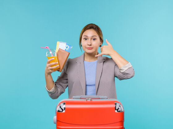 欢呼正面图：度假中的女性手持饮料和蓝色背景旅行的机票度假旅行快乐风景举行