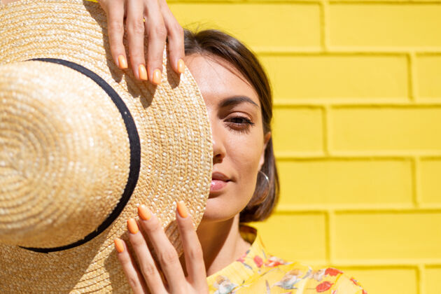 旅游黄砖墙上戴着黄色夏装和帽子的女人沉着而积极 享受着阳光明媚的夏日城市成人明亮