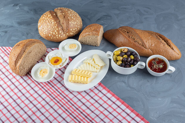 黄油在大理石桌上的桌布上放着早餐周围的切片面包和全面包美味可口盘子
