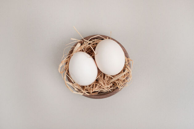 生的新鲜的鸡蛋和干草放在木碗里烹饪健康饮食家禽